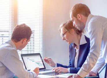 Trois individus dans un bureau face à un ordinateur illustrant le module décisionnel d'un ERP