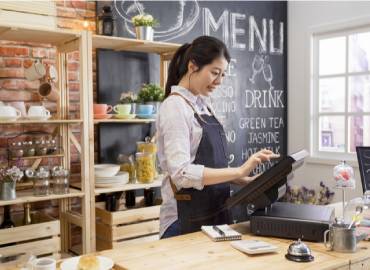 Femme devant une caisse enregistreuse dans un point de vente, illustrant le module Terminal Point de Vente d'un ERP